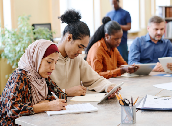 Diverse People filling out forms A diverse group of peolle sitting at a table filling out paperwork