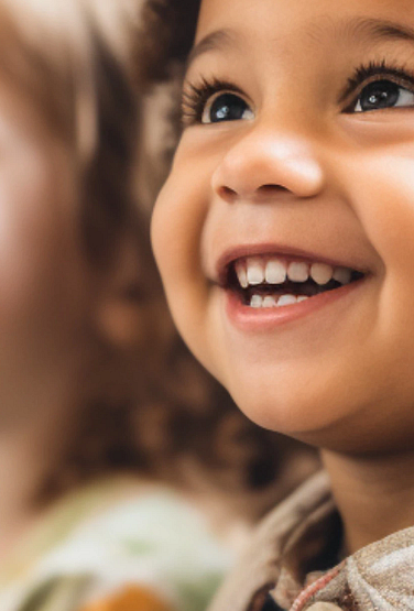 Mixed race group of toddlers, sitting in classroom and looking in awe at their teacher.